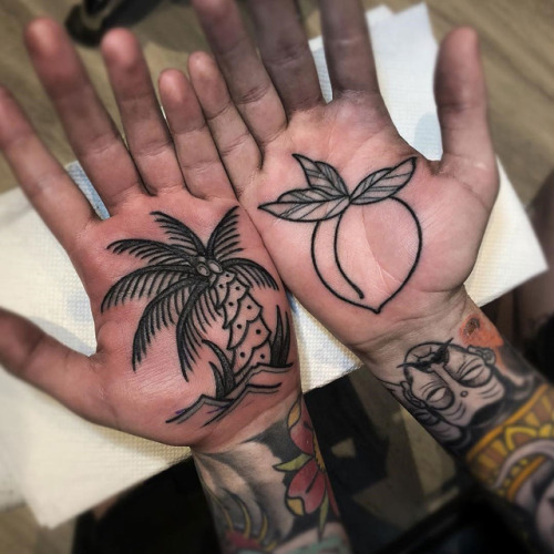 Black outlined palm tree and peach tattoo on both palm