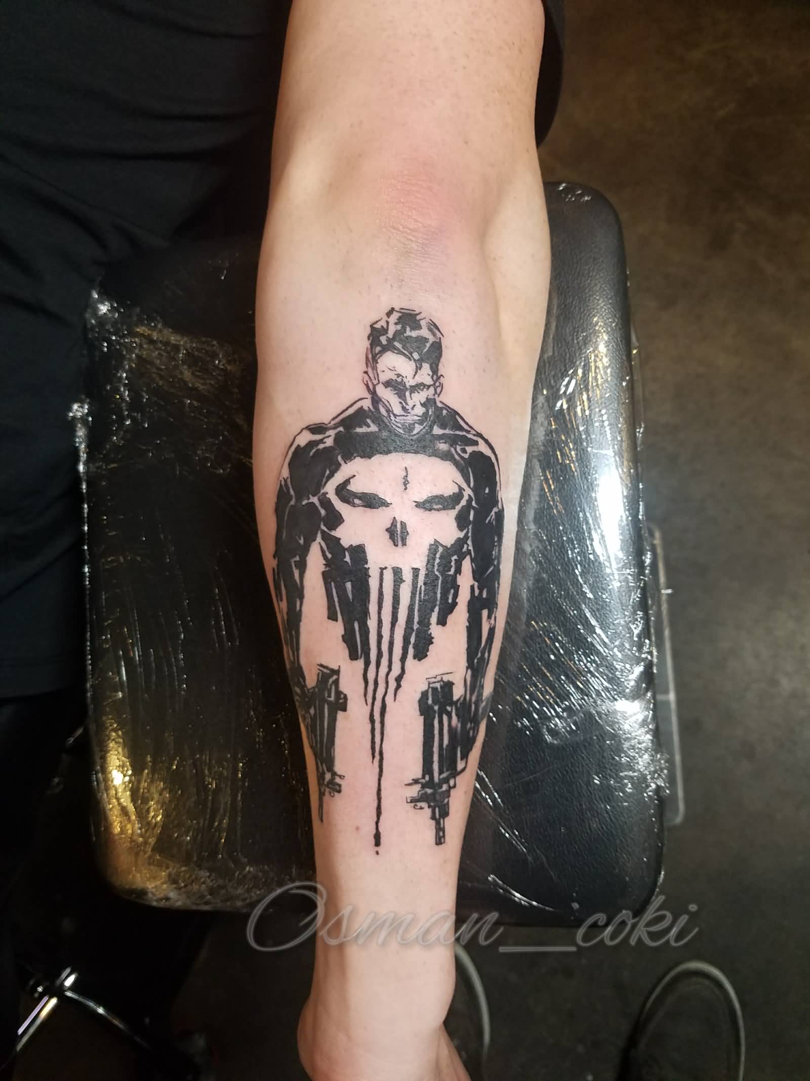 Black punisher man tattoo on forearm