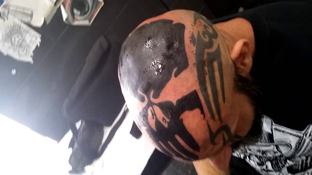 Black punisher skull tattoo on bald head for men