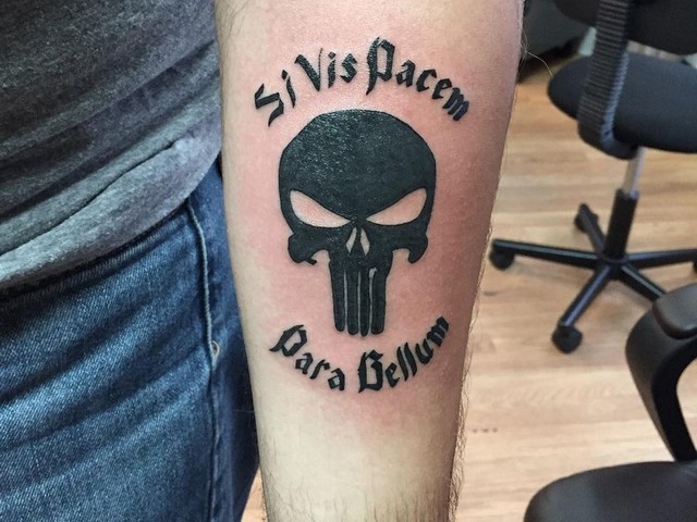 Black punisher tattoo with text on inner lower sleeve