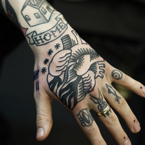 Black realistic heart tattoo on upper hand