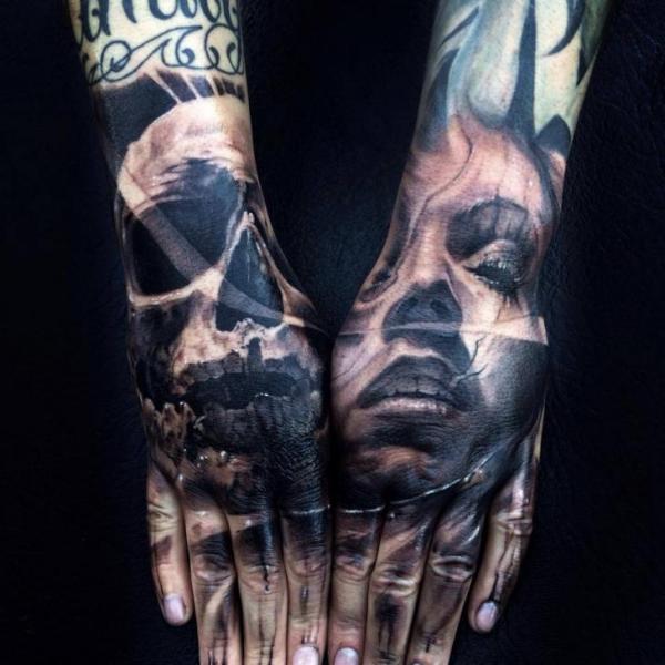 Black shaded skull and face tattoo on full upper hand by Jak Connolly