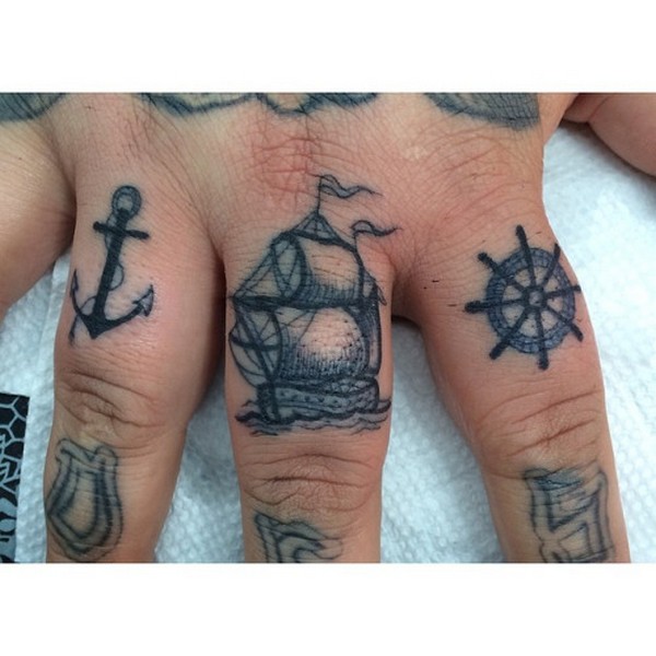 Black ship wheel and anchor tattoo on three mid fingers