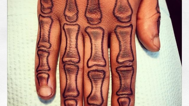 Black skeletal tattoo on upper fingers