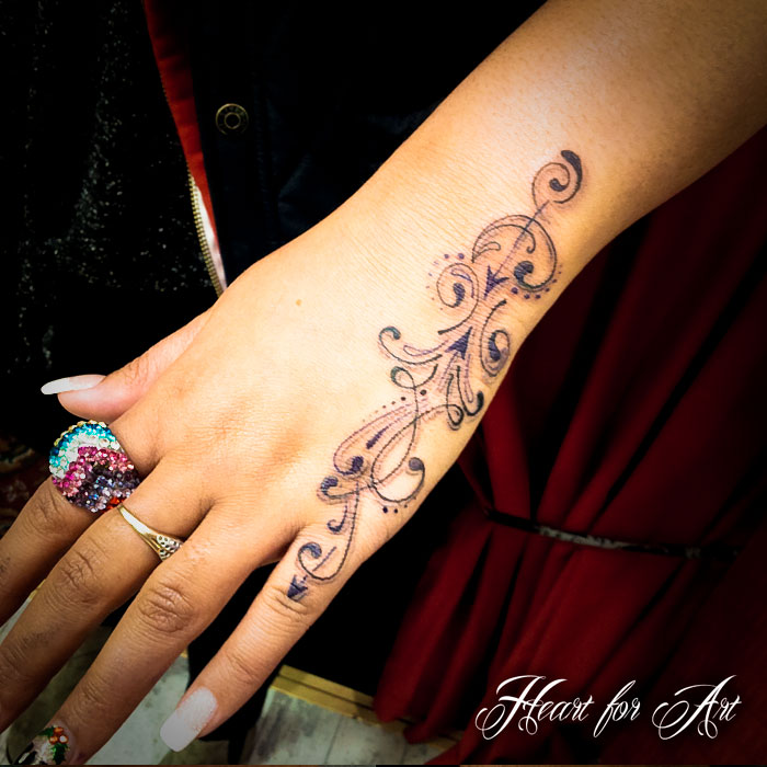 Black tattoo design on left hand for women