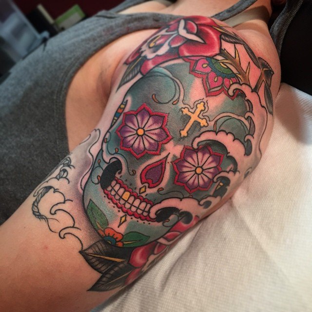 Colorful sugar skull tattoo on upper left arm for women
