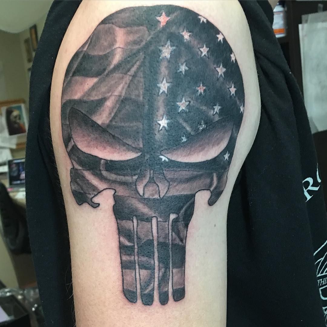 Grey and black shaded american flag punisher tattoo on upper arm
