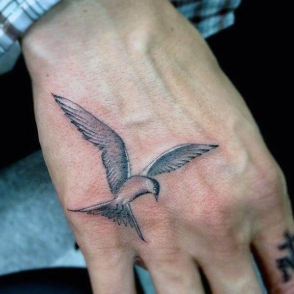 Grey and white flying dove tattoo on upper hand