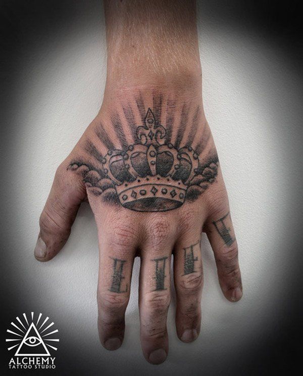 Grey shaded crown tattoo on upper hand