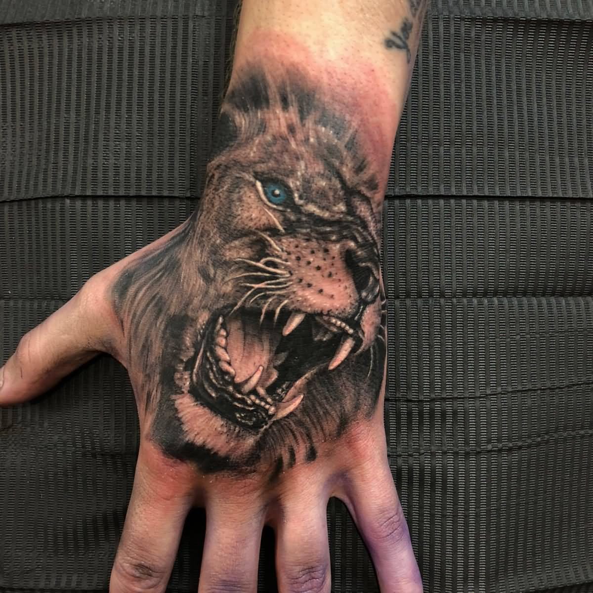 Grey shaded roaring lion tattoo on upper hand