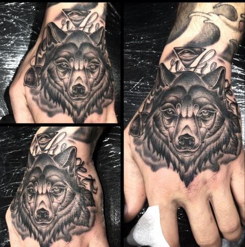 Grey shaded wolf tattoo on upper hand