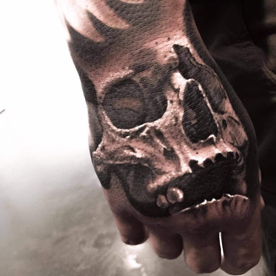 Black and grey shaded dangerous skull tattoo on right hand by Levi Barnett