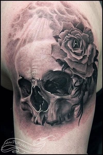 Black and grey shaded skull and rose tattoo on upper sleeve