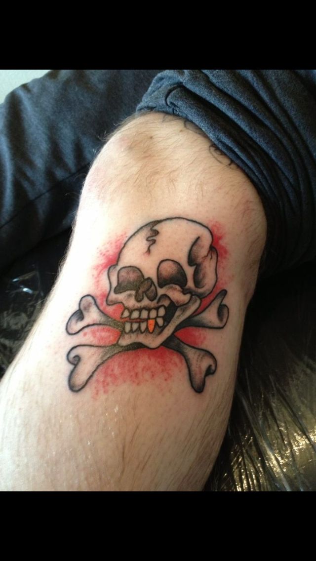 Black and red traditional crossbones skull tattoo on sleeve