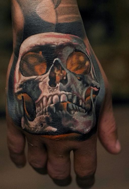 Black and yellow shaded skull tattoo on right hand