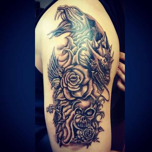 Black dragon and snake tattoo with skull and roses on upper arm