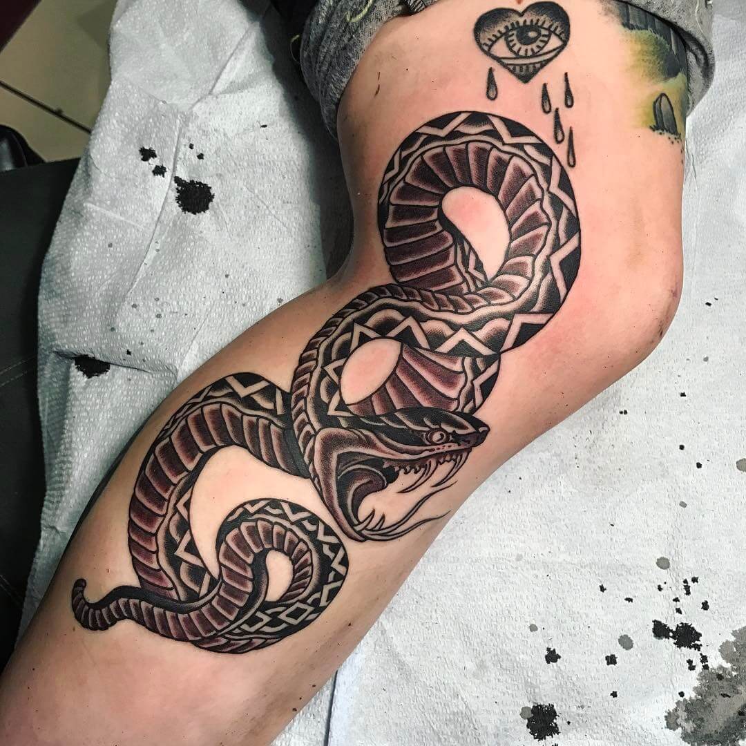Black dragon and snake tattoo with heart eye on arm