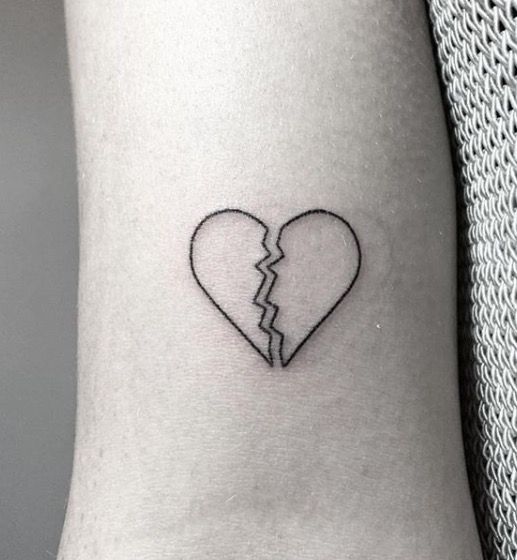 Black outlined broken heart tattoo on arm