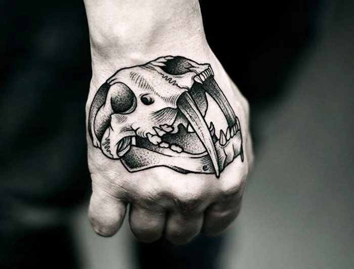 Black shaded dinosaur skull tattoo on right hand by Kamil Czapiga