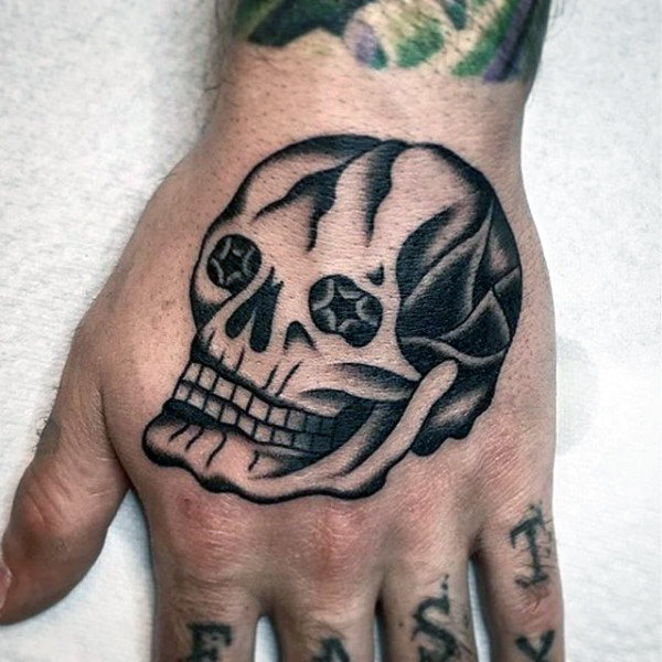Black shaded star eyes traditional skull tattoo on hand