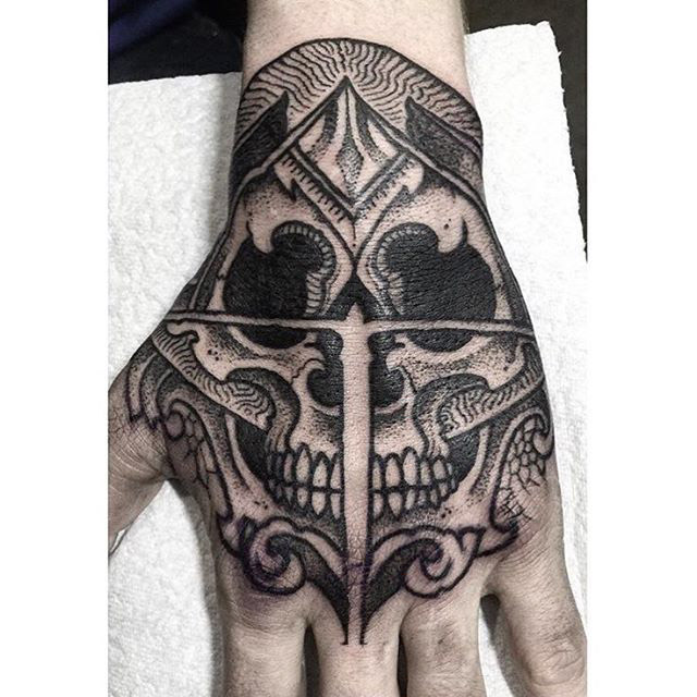 Black skull tattoo on left hand for men