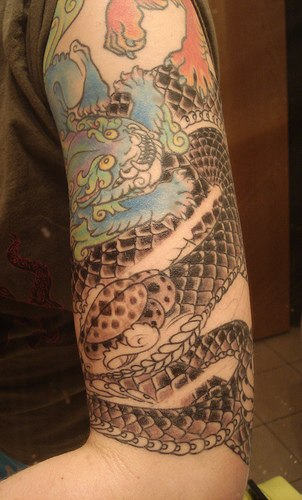 Colored dragon and snake tattoo on left bicep