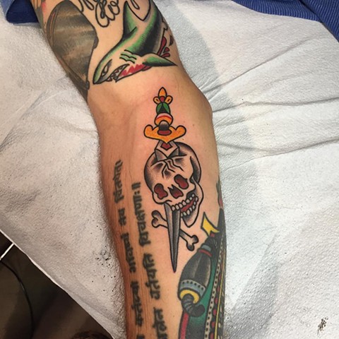 Colored traditional skull and sword tattoo on lower sleeve