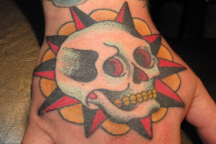 Colored traditional skull tattoo on hand