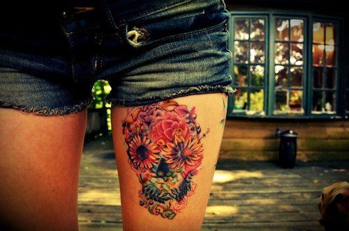 Colorful flower skull tattoo on left thigh for women