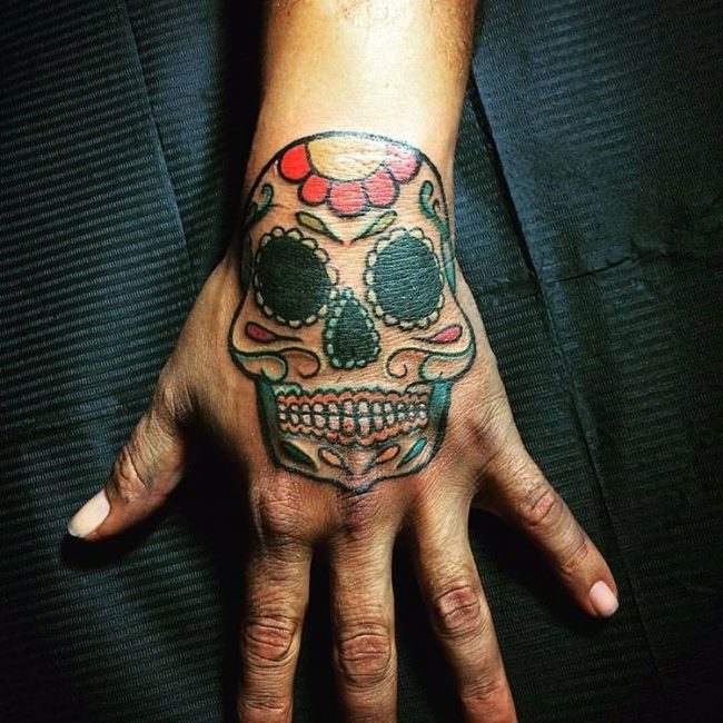 Colorful sugar skull tattoo on left hand