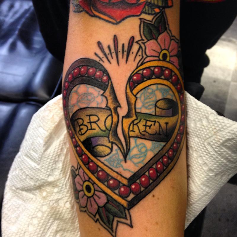 Colorful traditional cracking from mid broken heart tattoo on arm