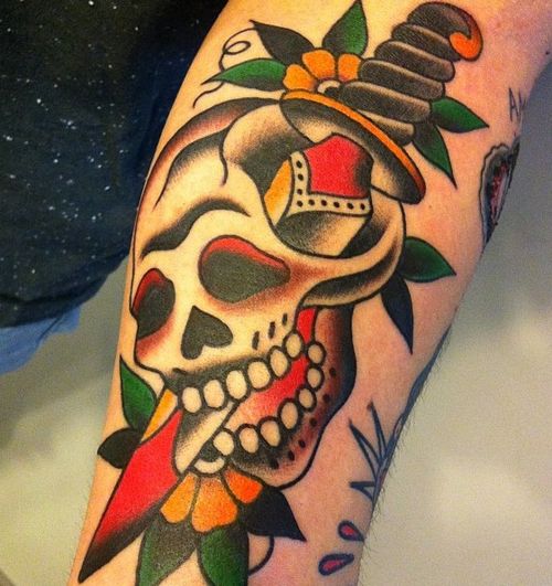 Colorful traditional skull with sword and flowers tattoo on body