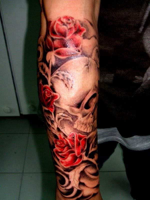Grey and red shaded skull and roses tattoo on full forearm
