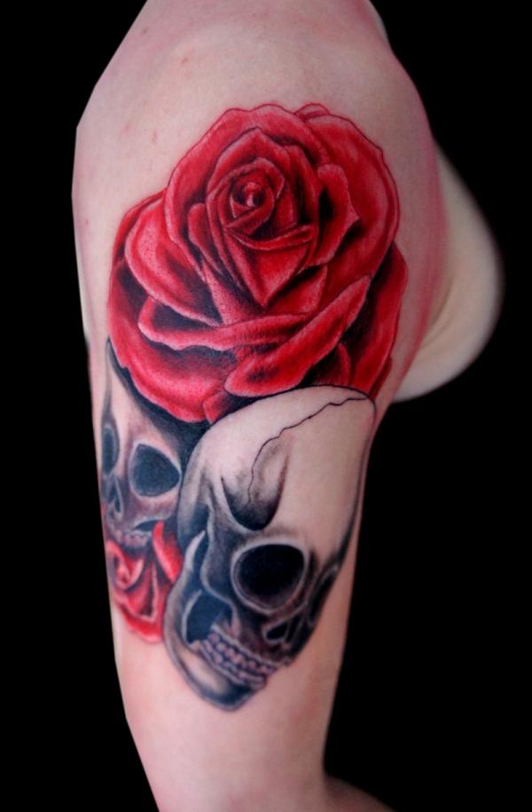 Grey and red shaded skulls and roses tattoo on upper arm for women