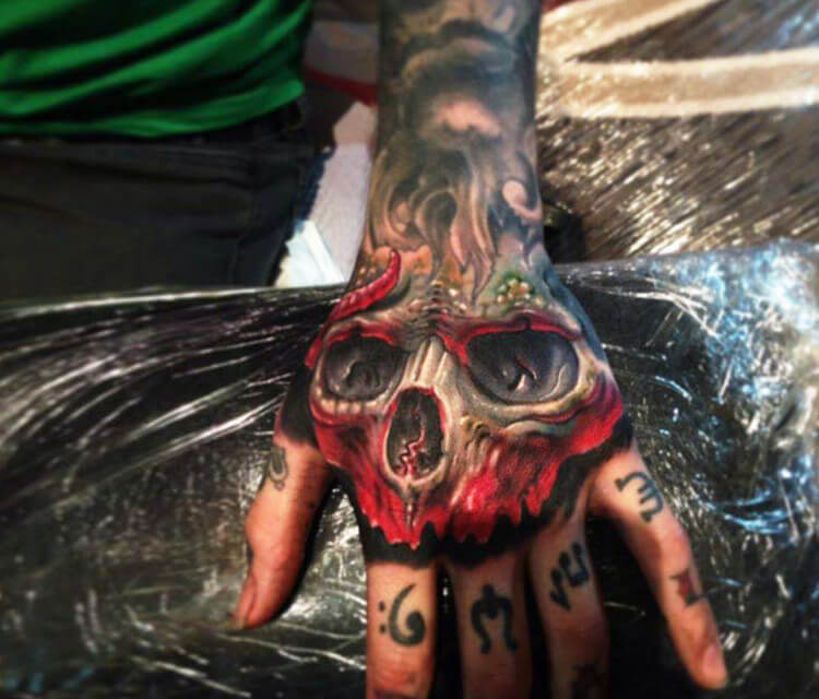 Grey and red skull tattoo on hand