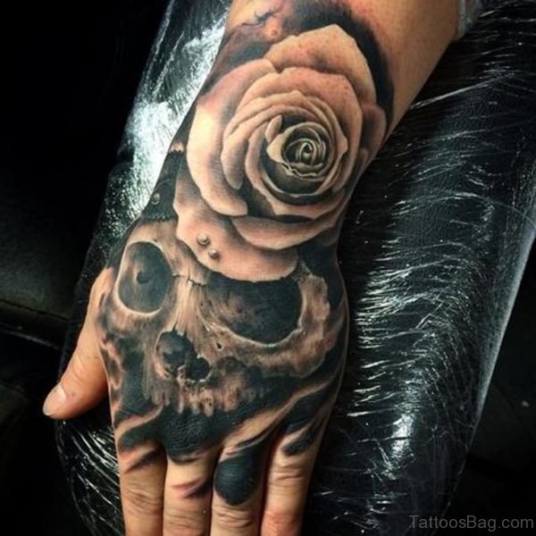 Grey rose and skull tattoo on hand