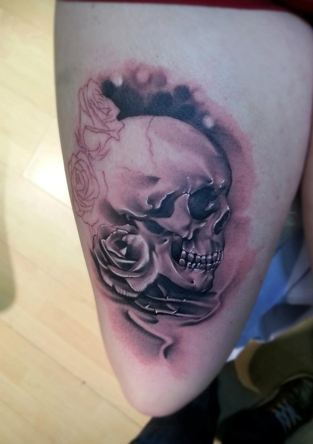 Grey shaded skull and rose tattoo on right thigh