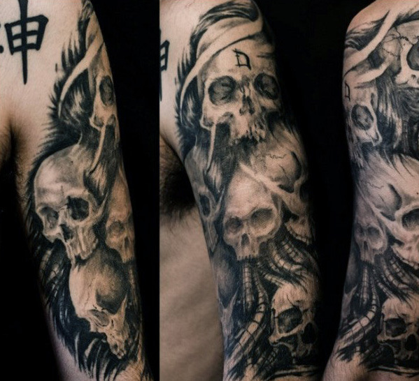 Grey shaded skulls tattoo on left upper sleeve