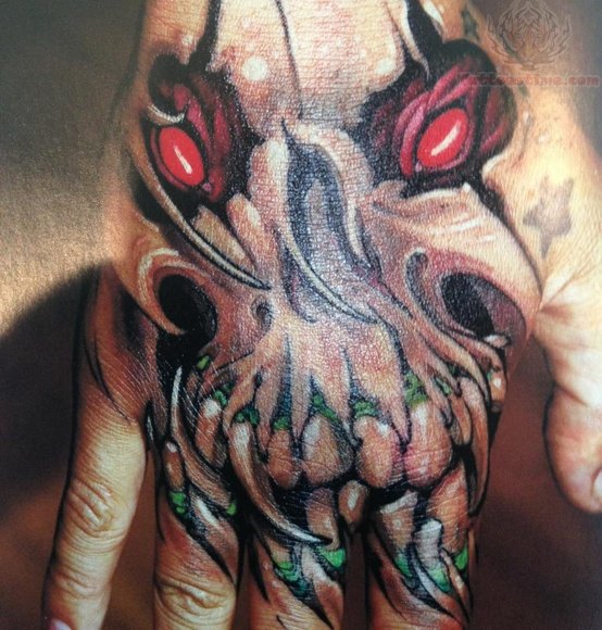 Red and black shaded skull tattoo on hand