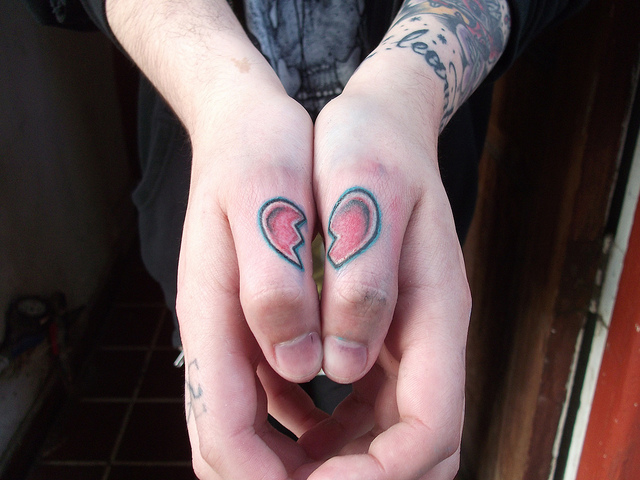 Red and black two halves broken heart tattoos on thumbs