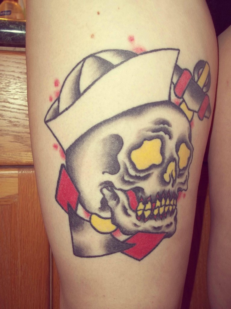 Red yellow and grey shaded traditional skull tattoo on right thigh