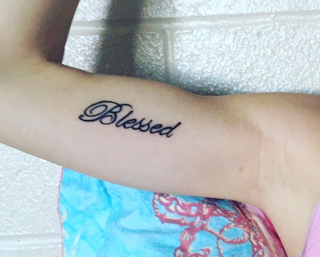 Black blessed tattoo on forearm for women