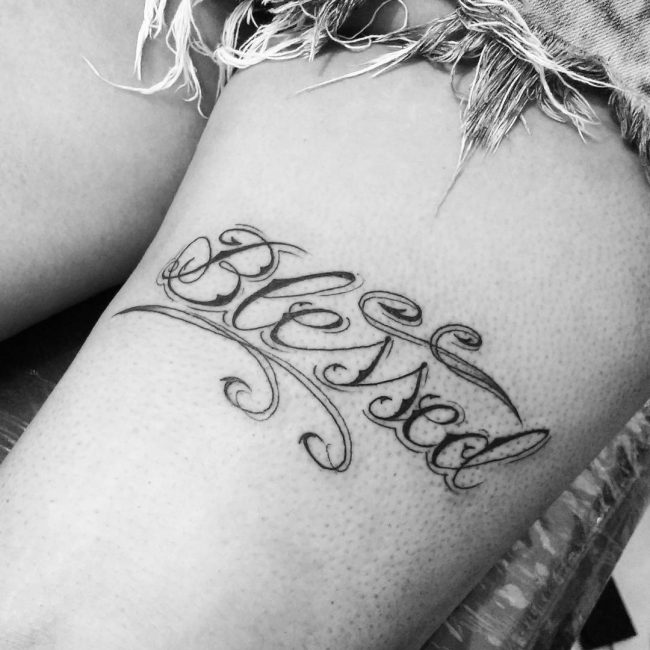 Black simple blessed tattoo on left thigh for women