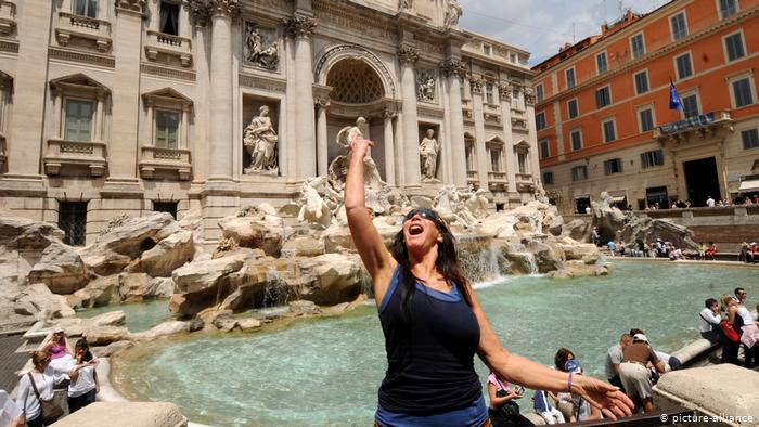 a tourist throws a coin into the Trevi Fountain