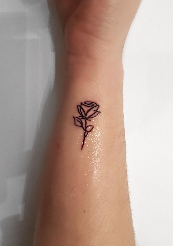 Black outlined small rose tattoo on forearm left side