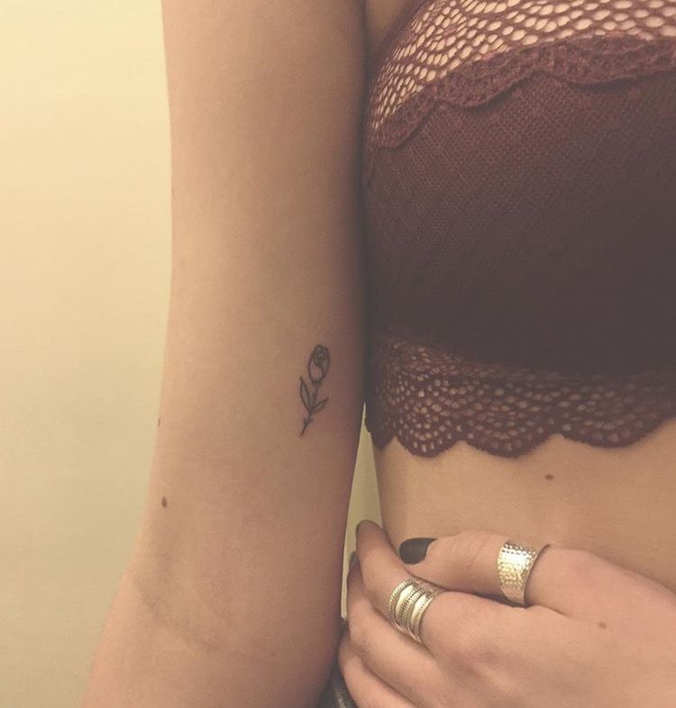 Black outlined small rose tattoo on inner arm for women