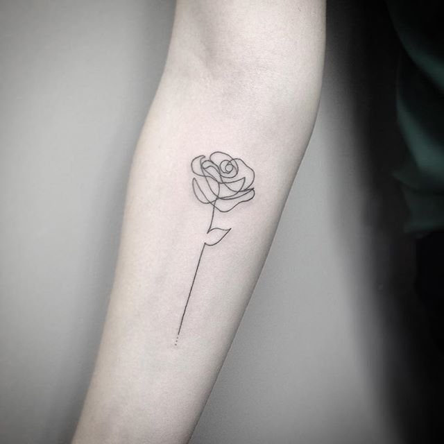 Black small rose tattoo on inner forearm