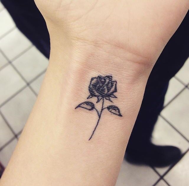 Black small rose tattoo on right inner wrist for women