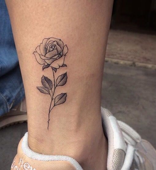 Grey shaded small rose tattoo on right lower leg